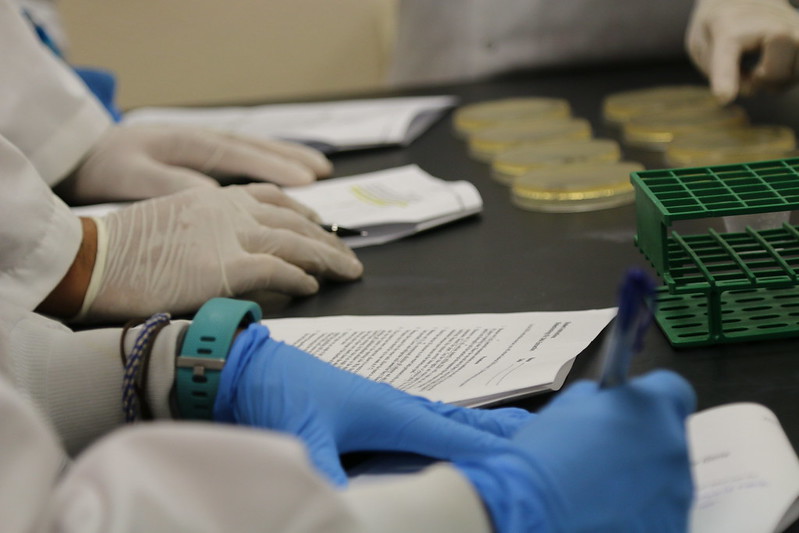 close-up of gloved hands, paperwork, and science equipment